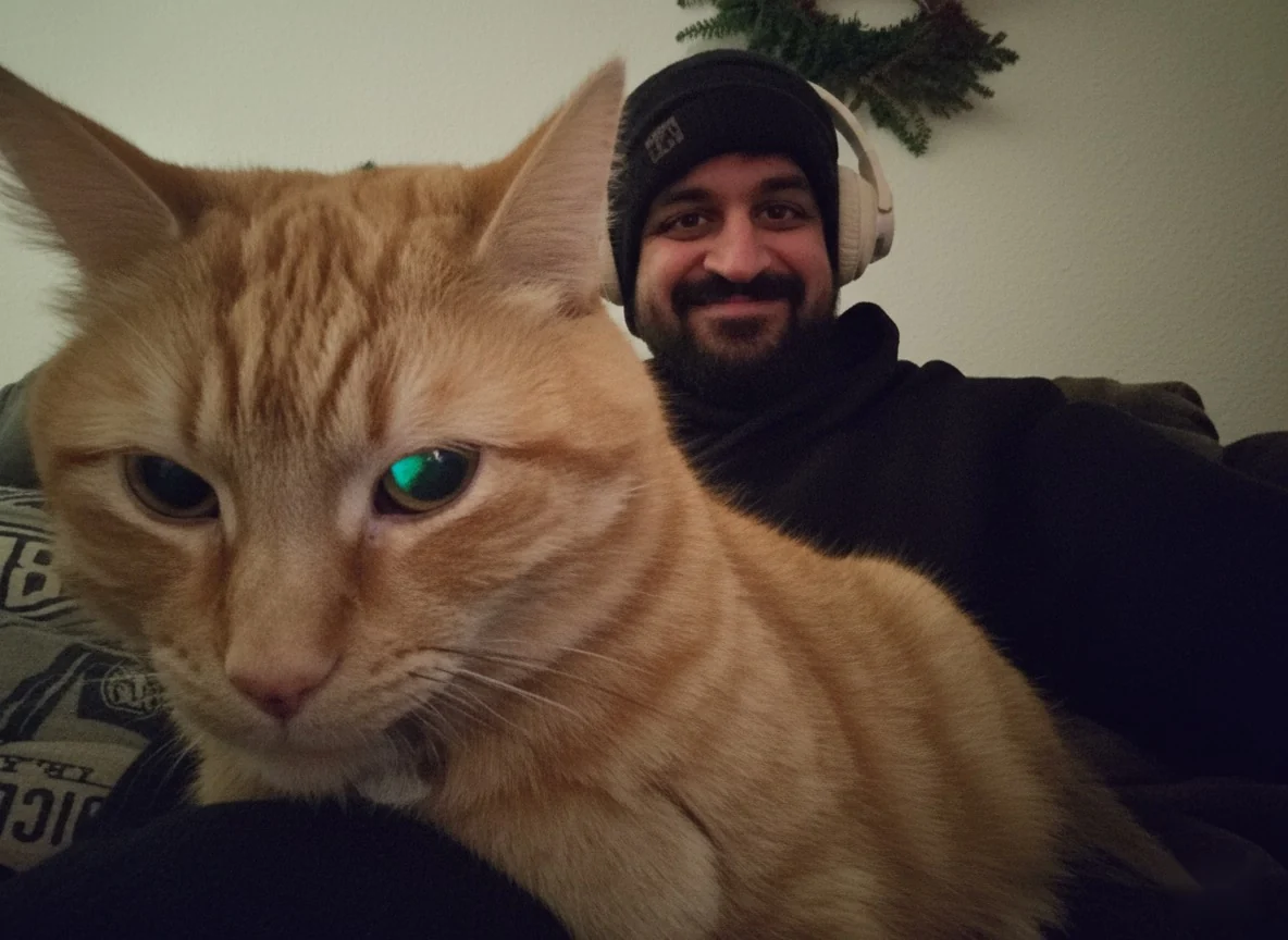 Miguel, an orange tabby cat, in the foreground with Jay smiling behind him